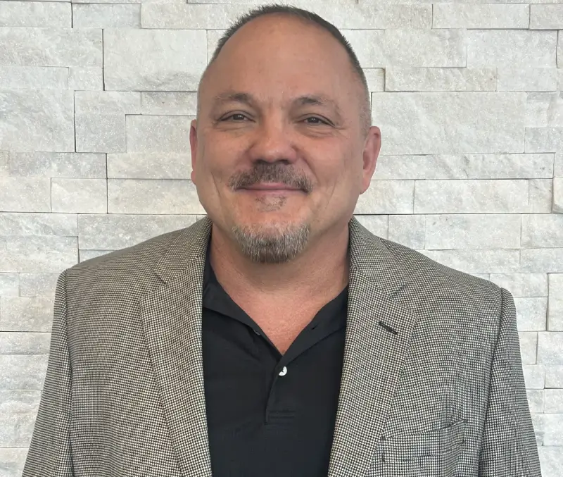 A man in a suit and tie smiling for the camera.